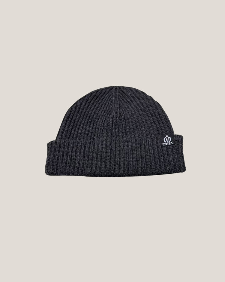 Dark gray knit beanie with a logo on a beige background