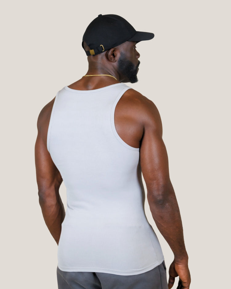 Man wearing a white tank top and black cap on a beige background