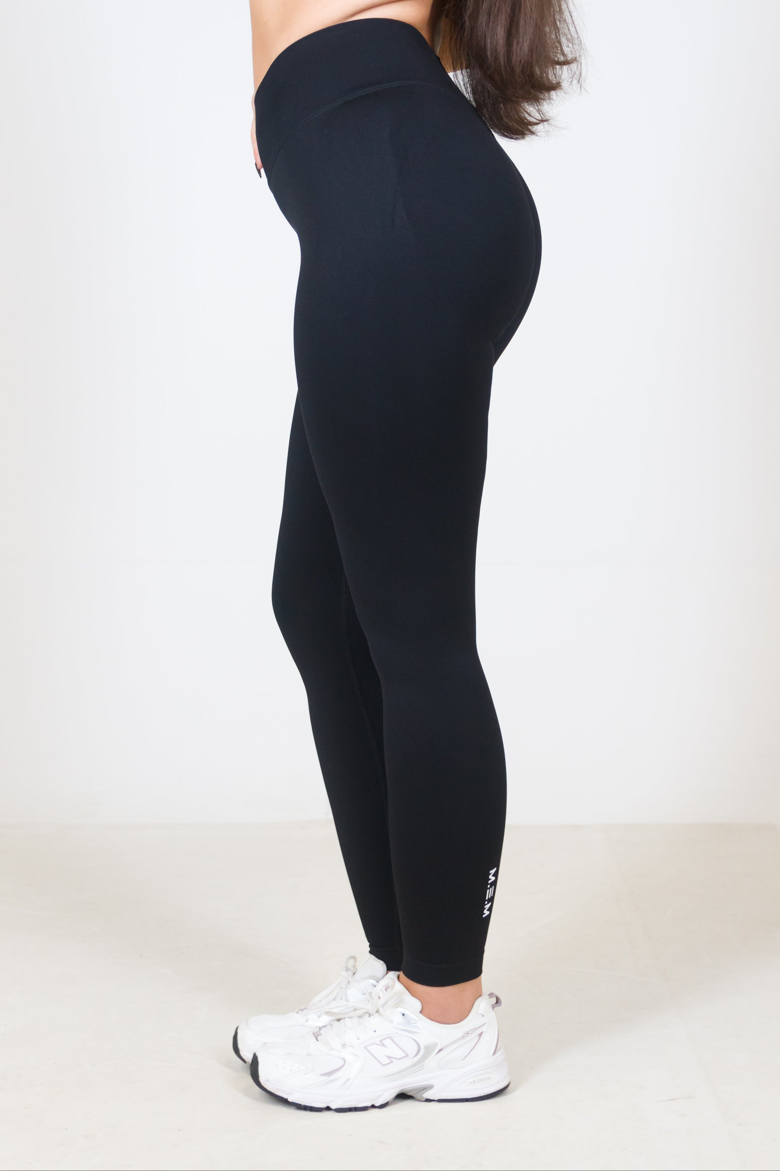 Person wearing black leggings and a black sports bra on a white background