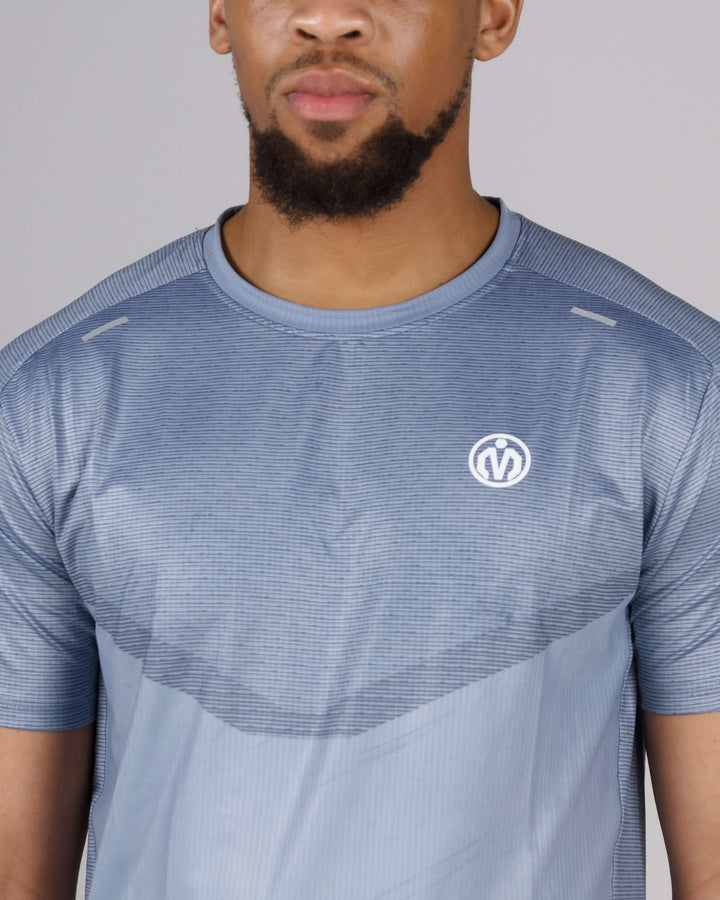 Man wearing MEM Pinnacle Dry-Fit T-Shirt with sweat-wicking technology in light blue color.