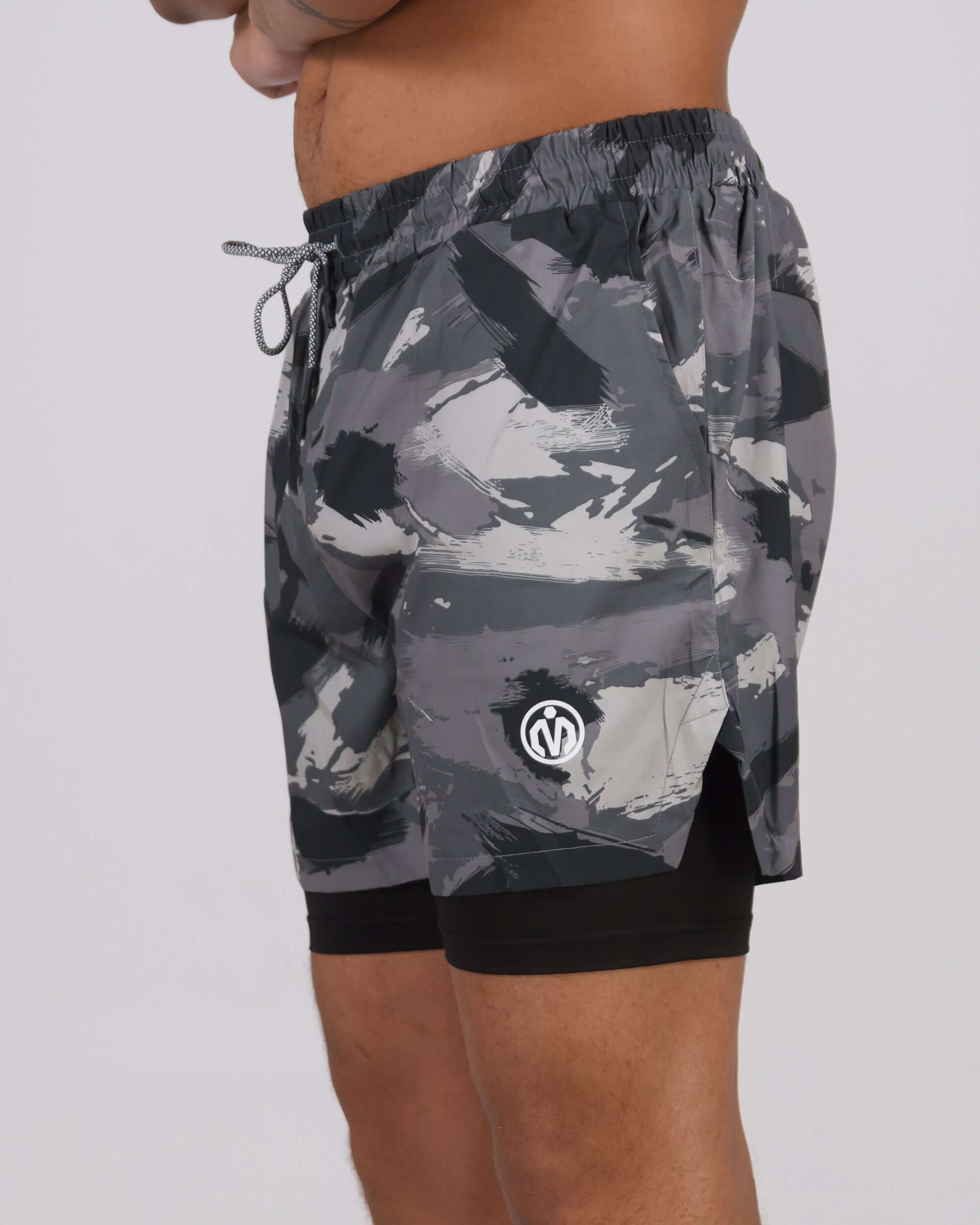 Grey camouflage Pinnacle Dry-Fit 2-in-1 shorts on a person, showcasing the innovative design and compression layer for maximized performance.