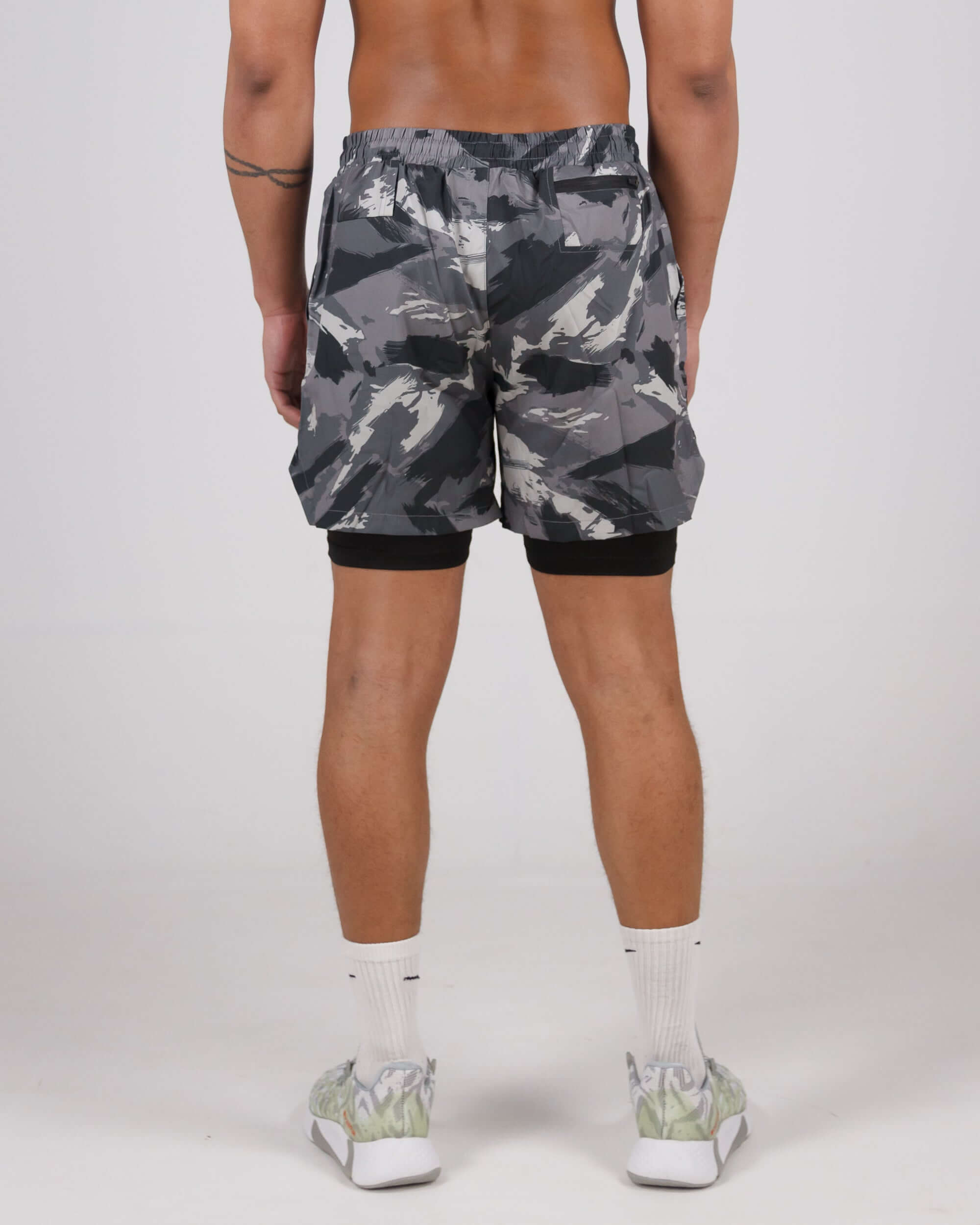 Man wearing grey camouflage Pinnacle Dry-Fit 2-in-1 Shorts from the back, showcasing the innovative design and compression layer.
