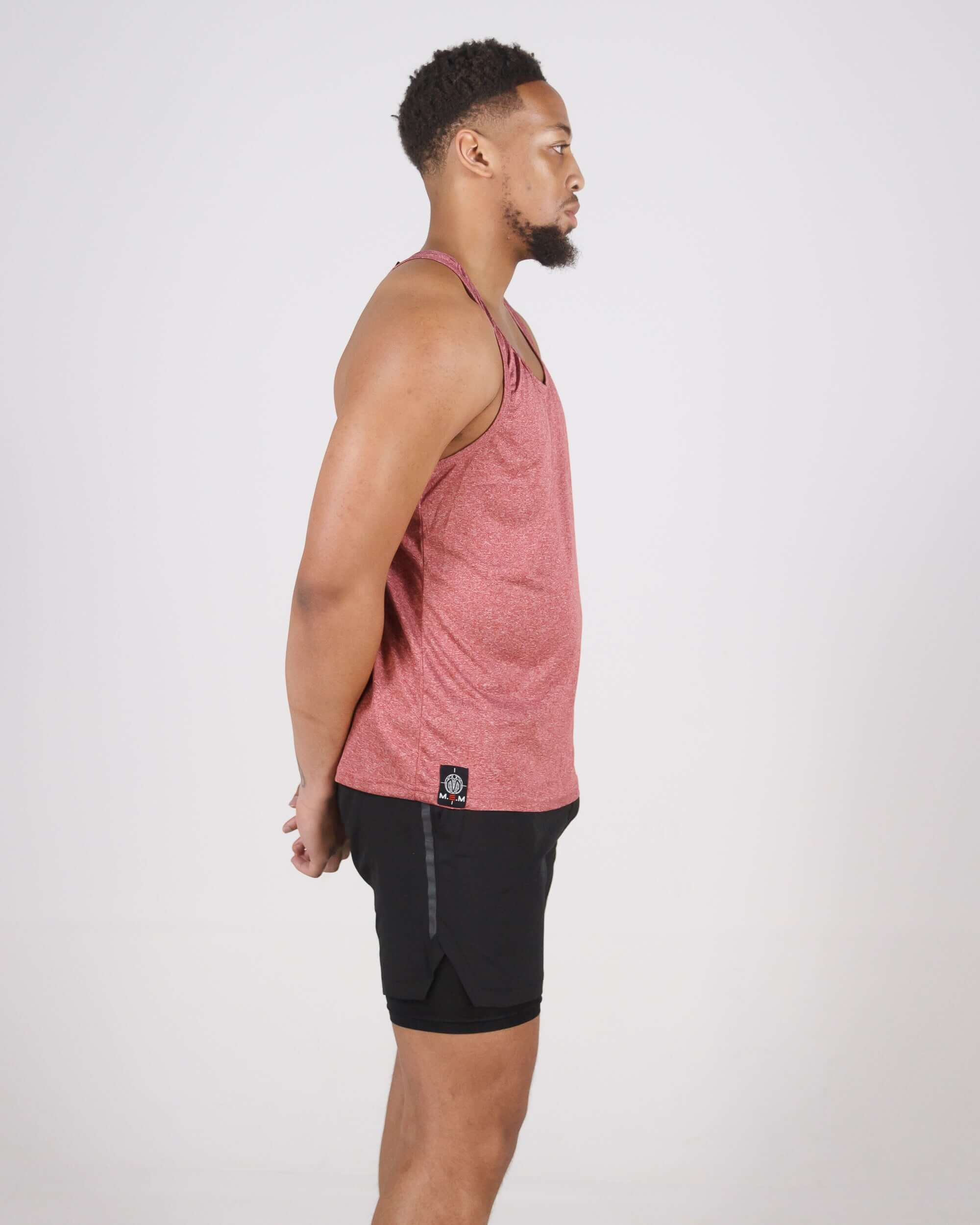 Man wearing Pinnacle Slim Fit Tank Top in pastel maroon; side view showcasing athletic build and tank top's sleek design